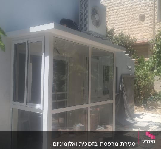 מבנה אלומיניום עם חלונות זכוכית ליד קיר חיצוני